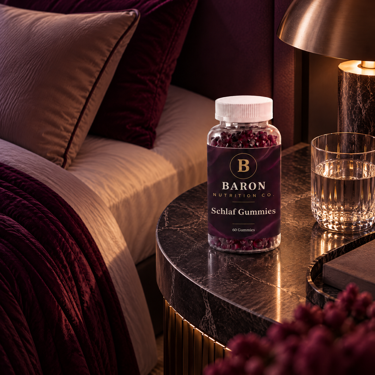 Baron Sleep Gummies jar on a marble nightstand next to a glass of water and a lamp